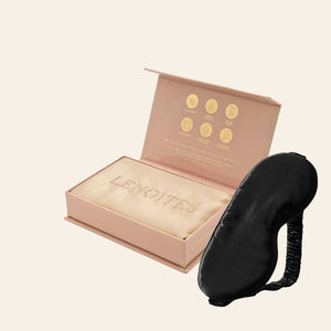 Pillowcase and Sleep Mask in Mulberry Silk by Lenoites featuring a black silk sleep mask and a beige mulberry silk pillowcase presented in an open blush pink box against a soft light background.