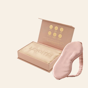 Pillowcase and Sleep Mask in Mulberry Silk by Lenoites featuring a pink silk sleep mask and a beige mulberry silk pillowcase presented in an open blush pink box against a soft light background.
