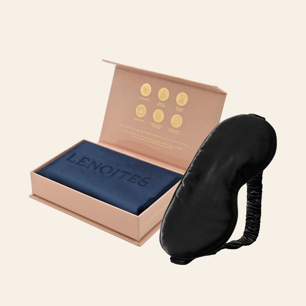 Pillowcase and Sleep Mask in Mulberry Silk by Lenoites featuring a black silk sleep mask and a blue mulberry silk pillowcase presented in an open blush pink box against a soft light background.