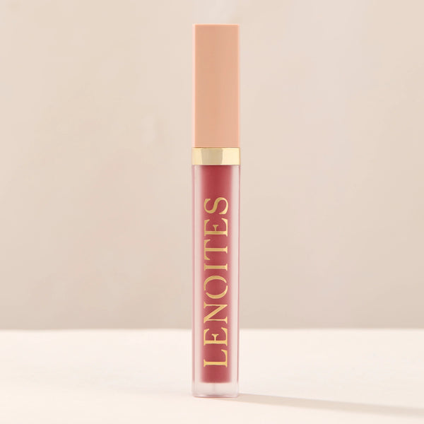 Tinted Lip Oil in Clever by Lenoites, featuring a sleek tube with a pink cap and clear body, showcasing the darker pink tint, displayed against a soft beige background.