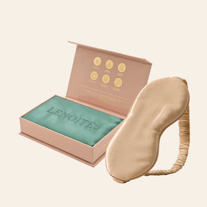 Pillowcase and Sleep Mask in Mulberry Silk by Lenoites featuring a beige silk sleep mask and a green mulberry silk pillowcase presented in an open blush pink box against a soft light background.