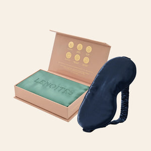 Pillowcase and Sleep Mask in Mulberry Silk by Lenoites featuring a blue silk sleep mask and a green mulberry silk pillowcase presented in an open blush pink box against a soft light background.