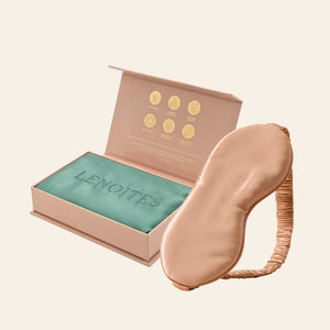 Pillowcase and Sleep Mask in Mulberry Silk by Lenoites featuring a rosegold silk sleep mask and a green mulberry silk pillowcase presented in an open blush pink box against a soft light background.