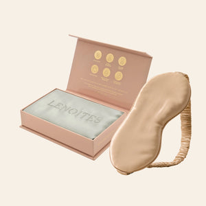 Pillowcase and Sleep Mask in Mulberry Silk by Lenoites featuring a beige silk sleep mask and a grey mulberry silk pillowcase presented in an open blush pink box against a soft light background.