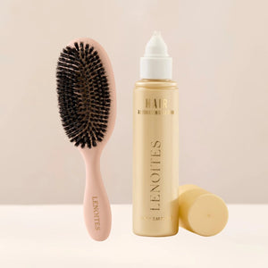 The Hair Growth Duo by Lenoites featuring a light pink hairbrush and the Hair Growth Serum in a transparent bottle with a golden tone, styled against a soft light beige background.