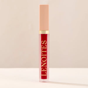 Tinted Lip Oil in Prestigious by Lenoites, featuring a sleek tube with a pink cap and clear body, showcasing the rich red tint, displayed against a soft beige background.