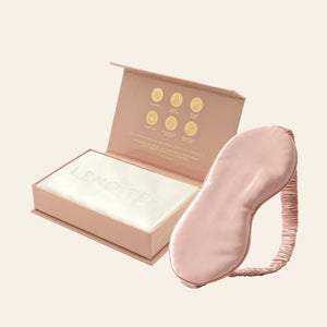 Pillowcase and Sleep Mask in Mulberry Silk by Lenoites featuring a pink silk sleep mask and a white mulberry silk pillowcase presented in an open blush pink box against a soft light background.